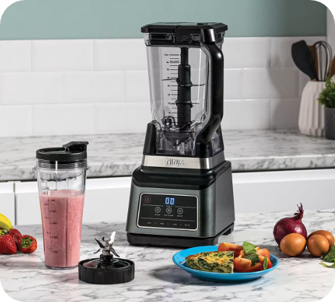 Ninja multi-serve jug blender with a smoothie and plated meal on a countertop