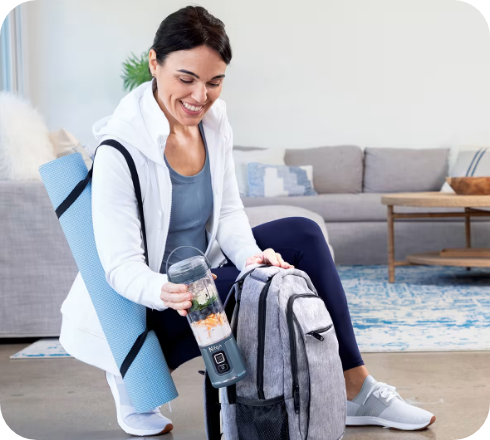Woman packing a portable Ninja blender into a bag after a workout